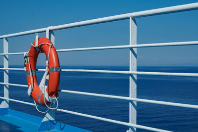 A red lifebuoy hangs on board a ferry cruise ship against the backdrop of a blue sea a cloudless sky