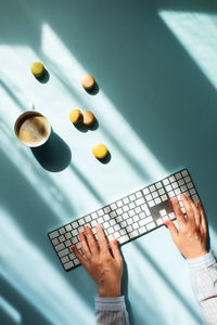 Cup of coffee and macaroons in sunlight and women hands typing on the keyboard.