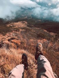 Low section of person relaxing on land against sky