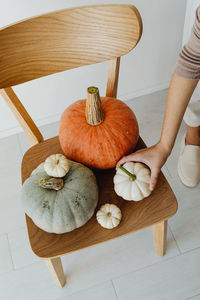 Midsection of woman holding pumpkin on table
