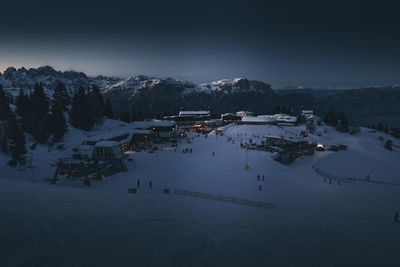 High angle view of buildings by mountain against sky during winter