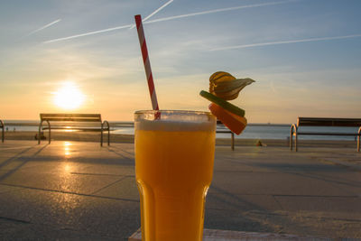 Close-up of drink on beach against sky during sunset