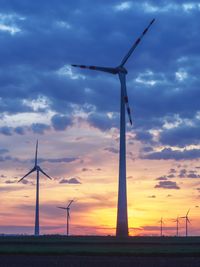 Windmill on field against sky during sunset