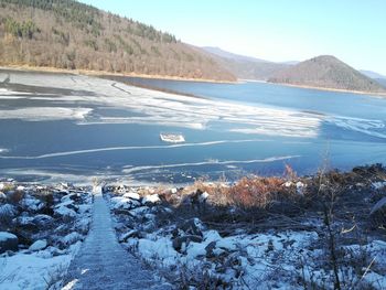 Scenic view of frozen lake by mountains against sky