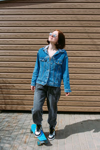 Portrait of young woman standing against brick wall