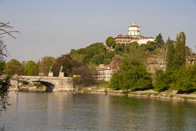 Bridge over river by building against sky