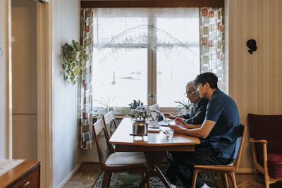 Side view of male caregiver discussing over medical reports with senior man at home