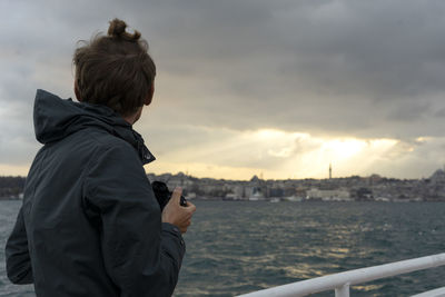 Man photographing by city against sky