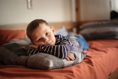 Thoughtful serious offended boy hugs a pillow on the couch, concept children's problems loneliness.