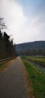 Empty road amidst trees against sky