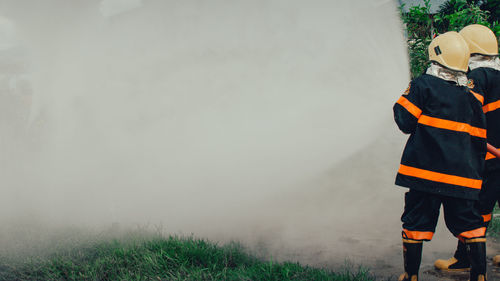 Firefighters spraying water while standing on field 