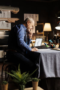 Side view of man using laptop while sitting on sofa at home