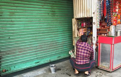 Full length of man standing on shutter of store