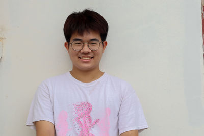 Portrait of young man standing against wall