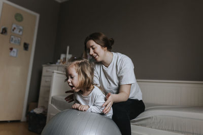 Mother supporting disabled child on fitness ball