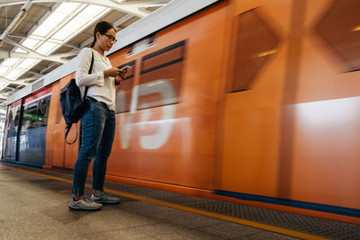 Woman standing by train at railroad station platform