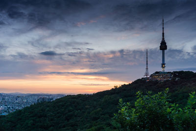 Communications tower and buildings against sky during sunset