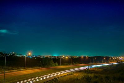 Light trails on street against sky at night