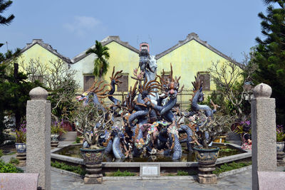 Statues against trees and plants against sky