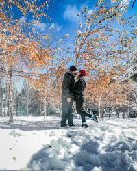 Side view of couple kissing while standing on snow covered land