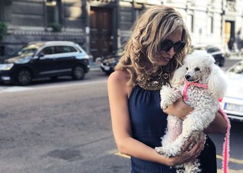 Woman with dog standing on street in city