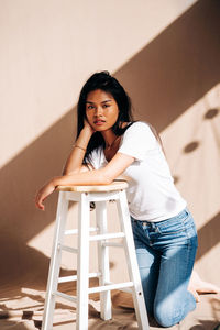 Portrait of woman sitting against wall at home