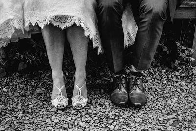 Low section of bride and bridegroom sitting outdoors