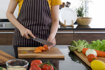 Midsection of woman preparing food in kitchen at home