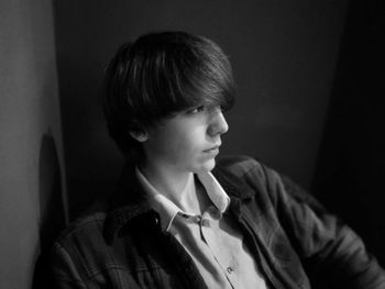 Close-up of teenage boy sitting against wall