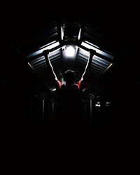 Rear view of silhouette person standing in illuminated tunnel