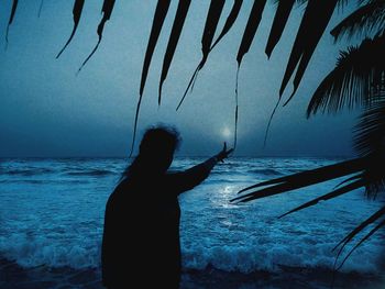 Silhouette man standing on beach against sky