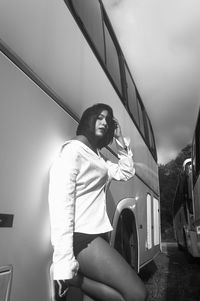 Young woman sitting on bridge against sky