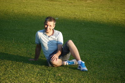 Portrait of mature man sitting on grassy field