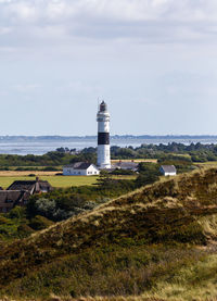 Lighthouse by sea against sky