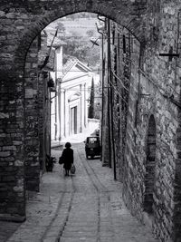 Rear view of woman walking on footpath amidst old buildings