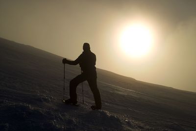 Silhouette man standing on mountain against sky during sunset