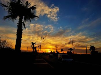 Silhouette trees against dramatic sky during sunset