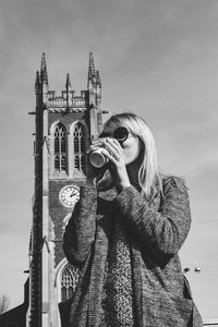 Low angle view of woman drinking against church