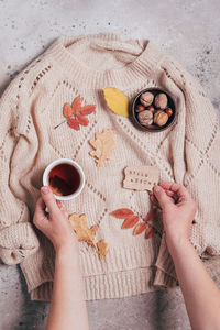 Cropped hand of woman holding tea over sweater