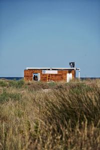 Beach house on field against clear sky