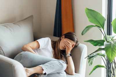 Young woman using mobile phone while sitting at home