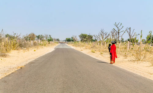 Mother and son standing on road against clear sky