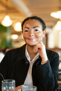 Portrait of young woman with vitiligo sitting in restaurant