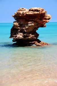 Rock formation in sea against clear sky