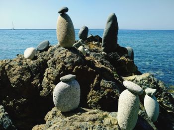 Close-up of rocks by sea against clear sky