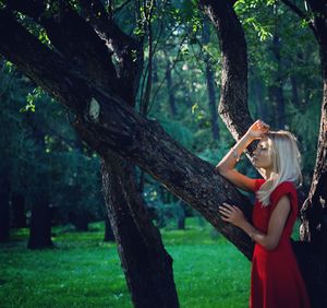 Woman standing on tree trunk in forest