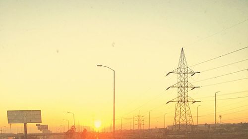 Low angle view of electricity pylon against sky during sunset