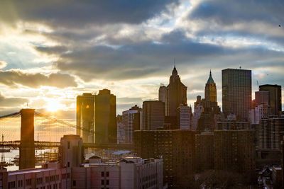 Modern buildings in city against sky during sunset