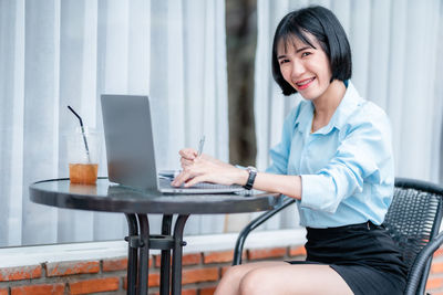 Young woman using laptop while sitting on table