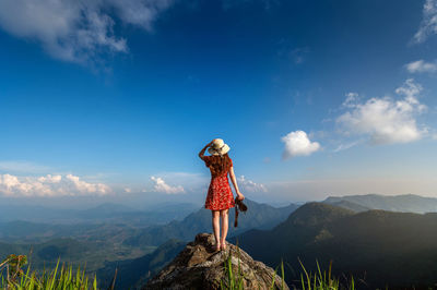 Rear view of woman standing on mountain against sky